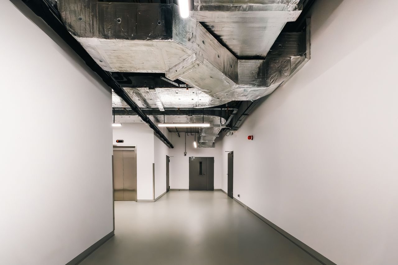 Spacious industrial hallway featuring exposed HVAC ductwork and modern design elements.